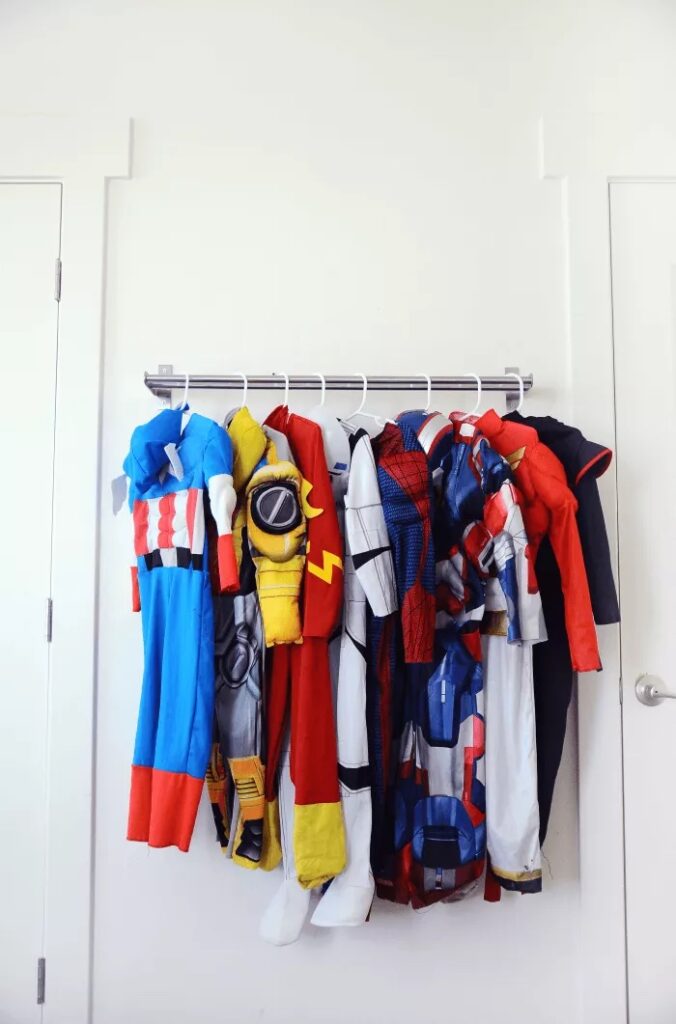 super hero costumes hanging on a towel rod 