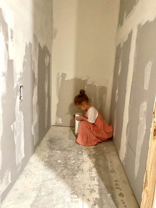 Little girl squatting in a hallway under construction. 