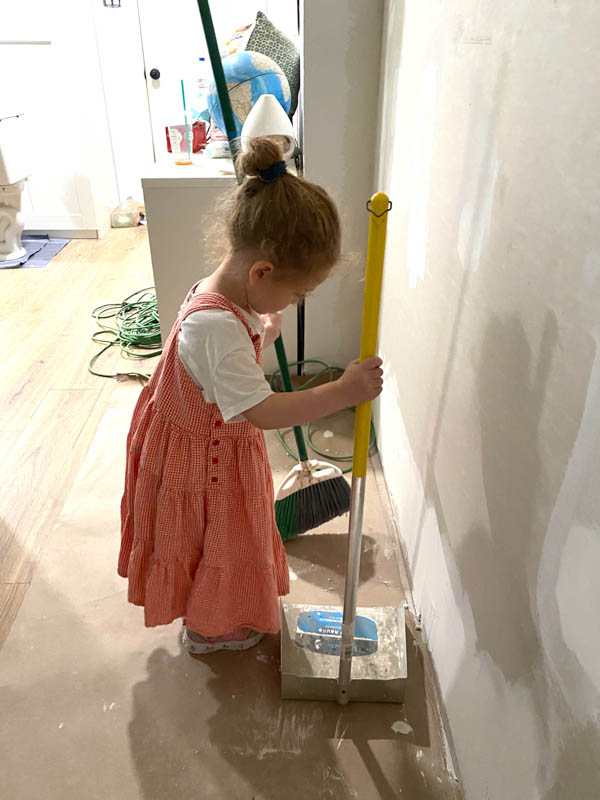 Little girl with a broom and dust pan sweeping in a kitchen under construction.