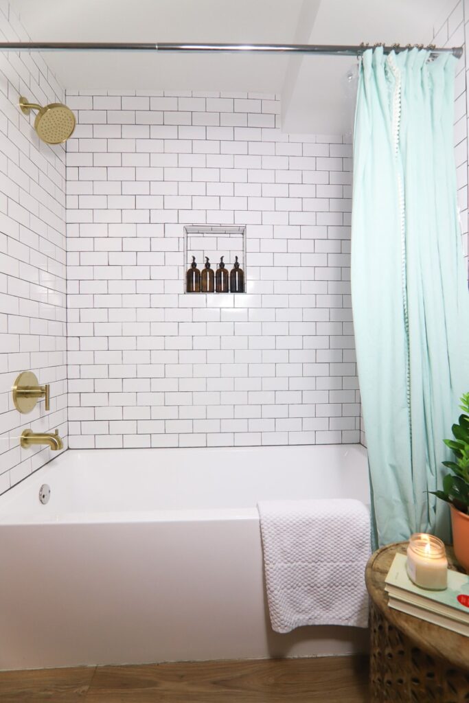 Bathroom shower with white subway tiles and ark grout.