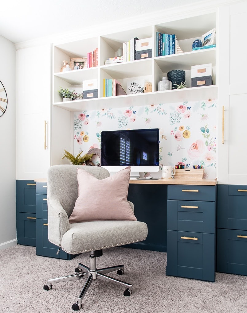 home office with built in desk and shelving and floral backdrop 