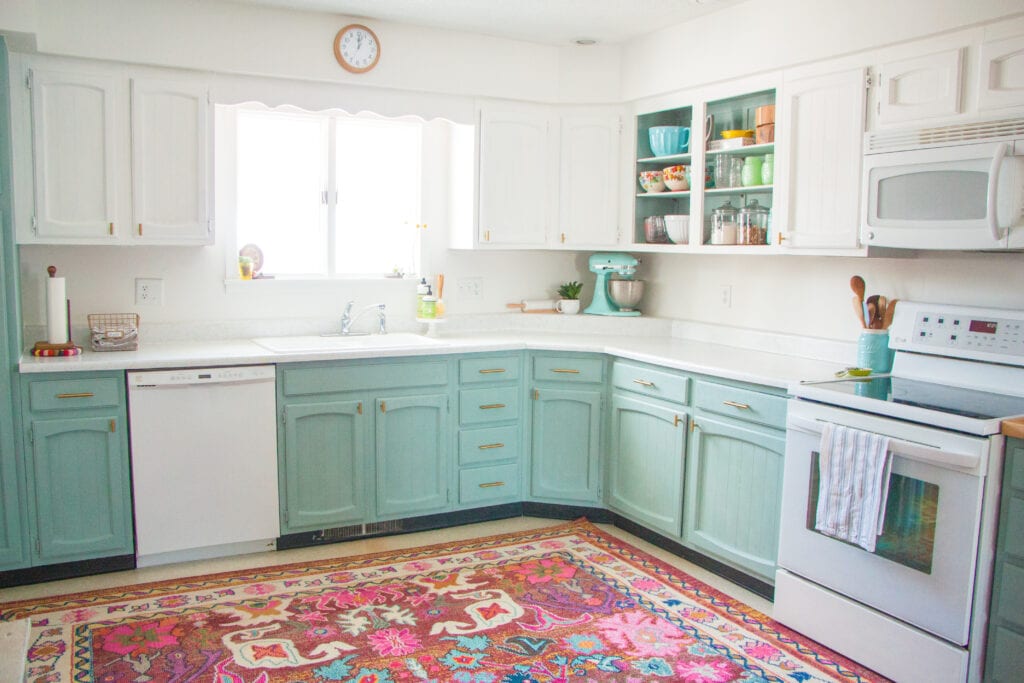 seafoam green painted lower cabinets against a large bright area rug