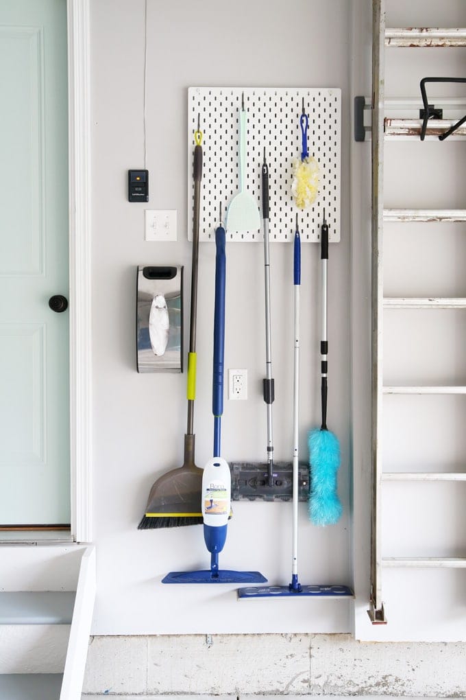 peg board organizing everyday items like brooms and dusters