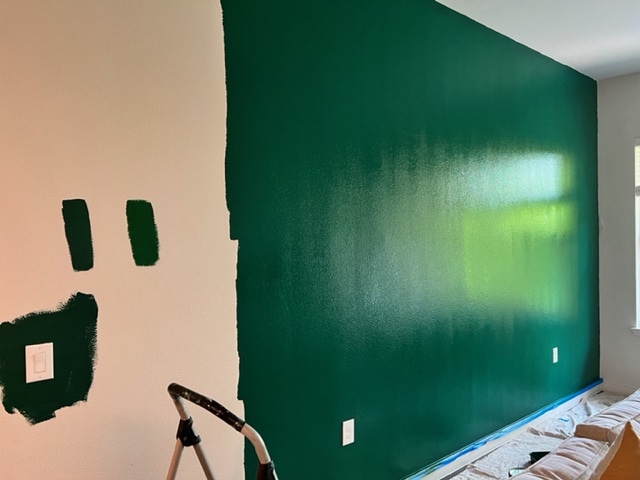 Green accent wall being painted in living room.
