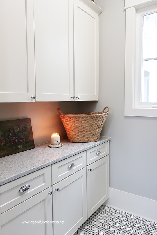 laundry room with white cabinets, and a lit candle on a decluttered countertop