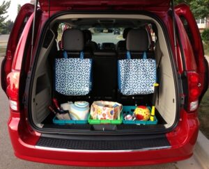 Red van with trunk open with bags for storage and three crates for storage