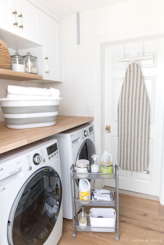 white and neutral laundry space with baskets and storage cart