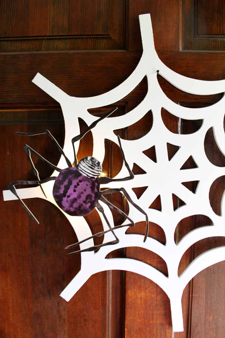 Wooden spiderweb cutout with a spider decal on top for Halloween wreath ideas.