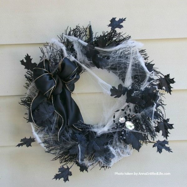 Spiderweb wreath design with black leaves and rhinestoned spiders.