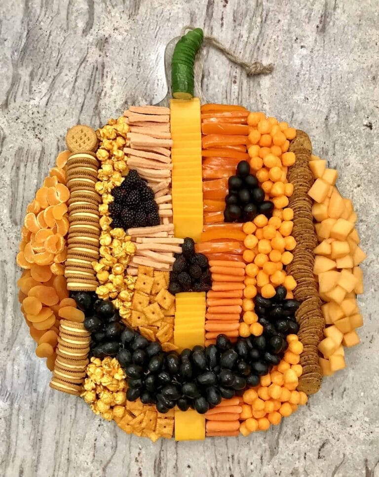 snack spread with cheese, veggies and other snacks in the shape of a jack-o-lantern