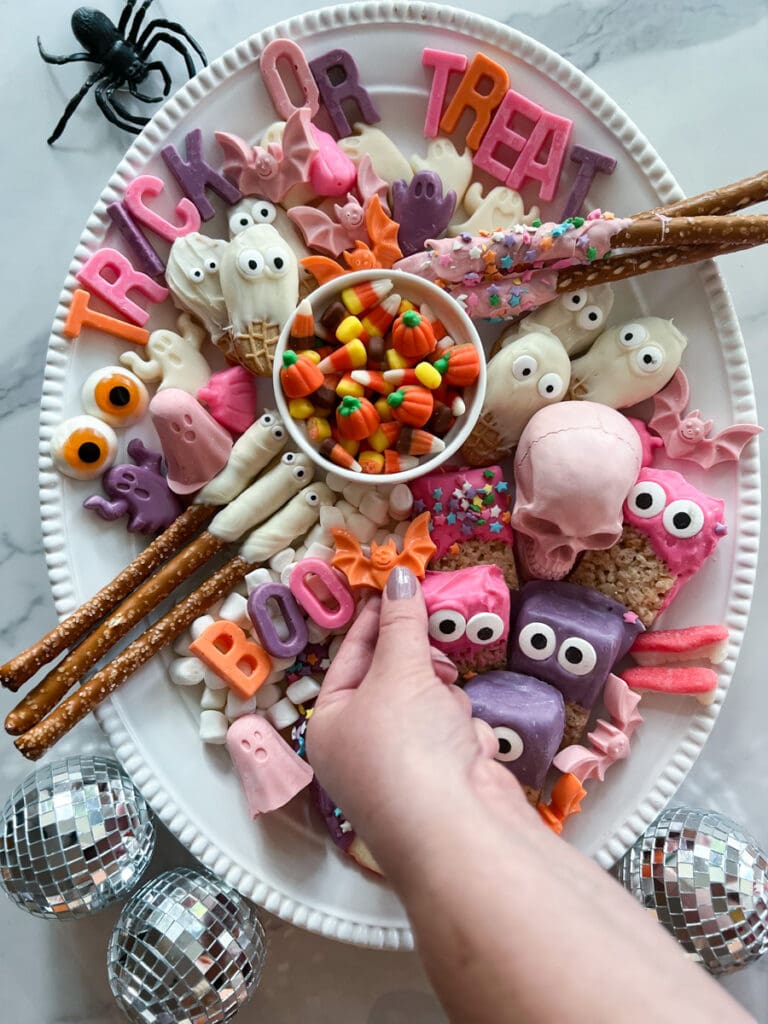 a hand reaching for a candy on a snack tray