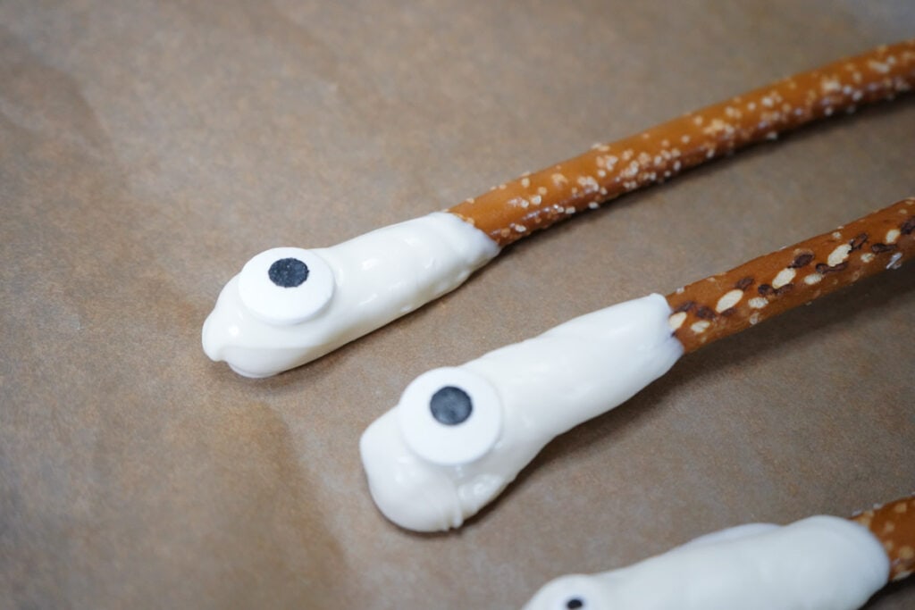 adding candy eye to candy dipped pretzels