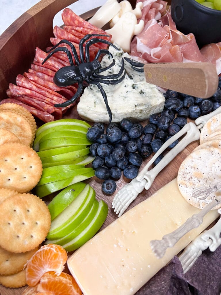 a plastic spider atop cheese and fruit tray