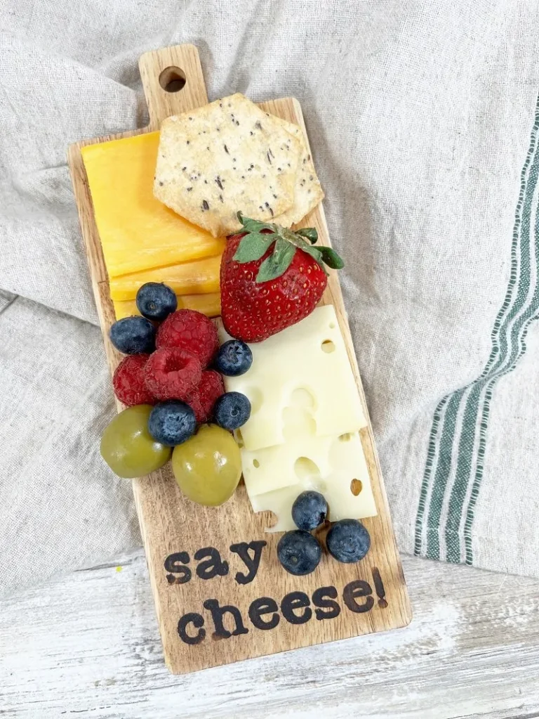wood burned cheese board with cheese and fruit on top 