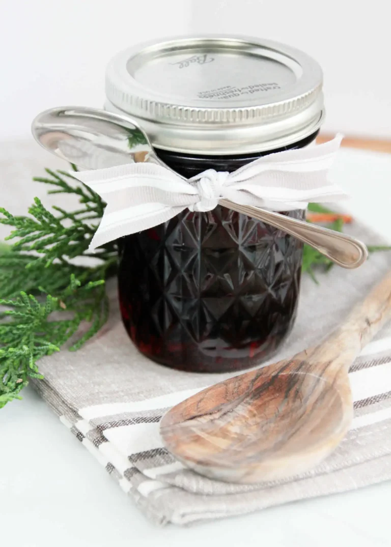 jar of whiskey infused maple syrup tied with ribbon and spoon