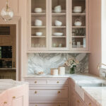 Pale pink color drenched kitchen with marble backsplash and counters.