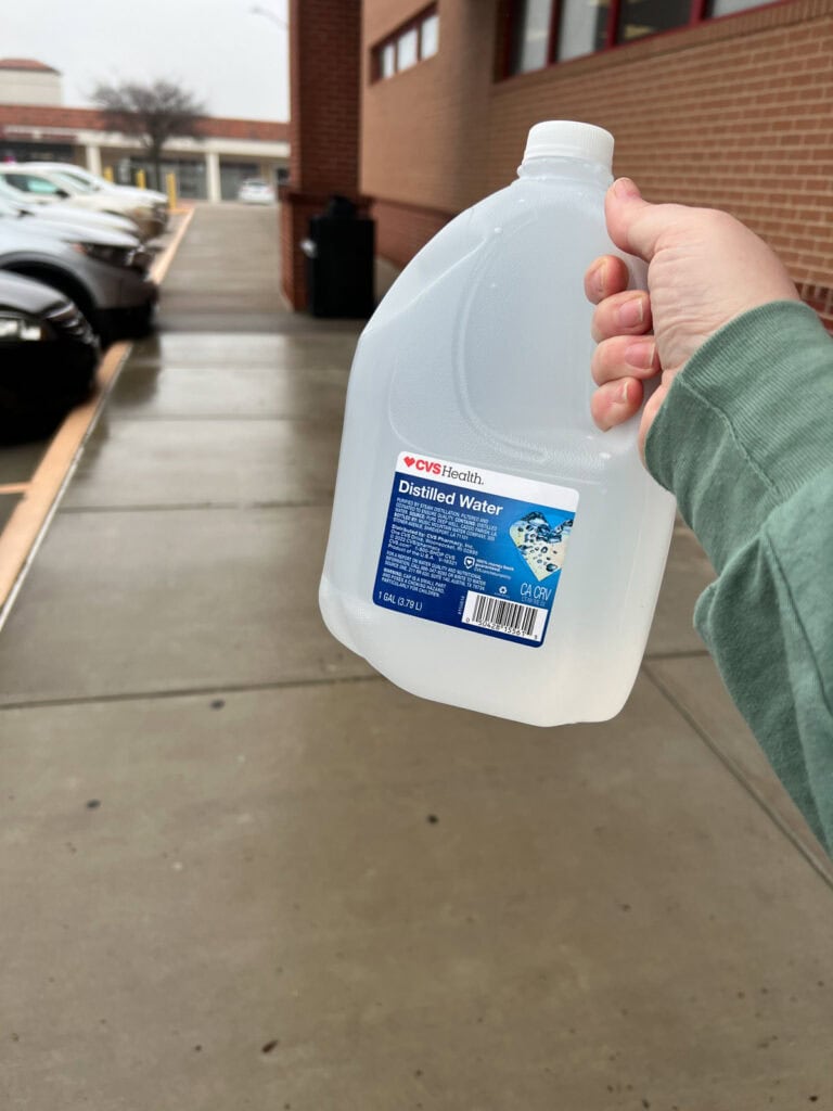 Holding up a gallon of distilled water.