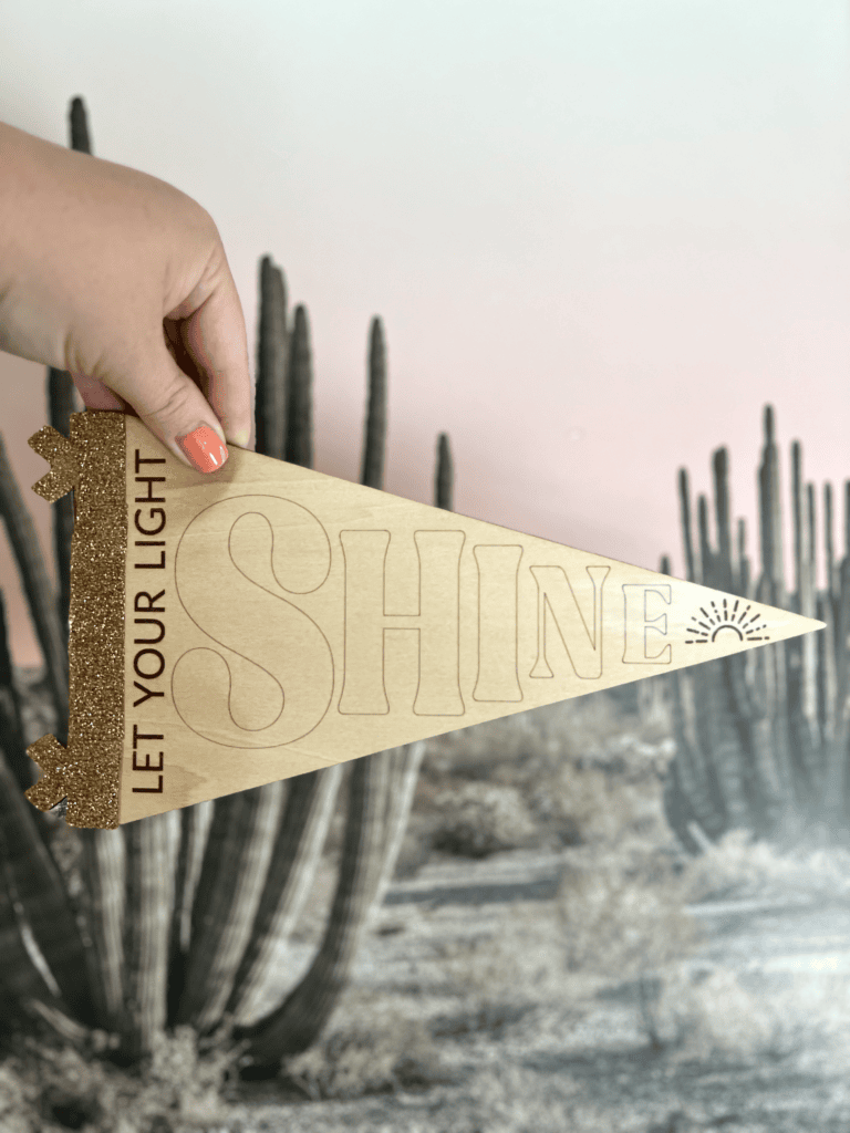Wooden sign that says "let your light shine" with glitter HTV on side.