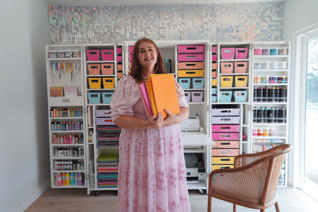 Woman holding a stack of colorful pink and orange paper