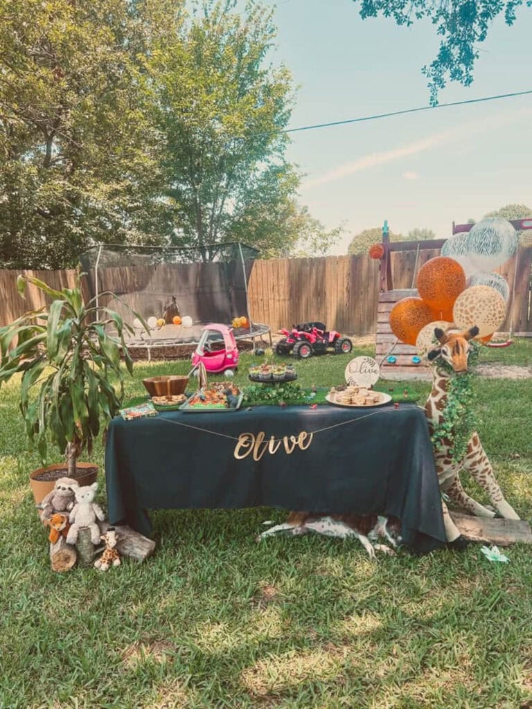 a table set up in a backyard to celebrate a 2 year olds Two Wild birthday