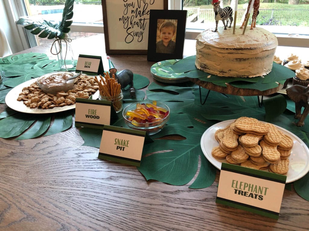 a decorated tablescape with food labels in front of plates of party foods