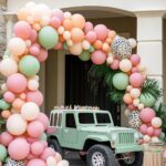 pink, coral and green balloon arch over green jeep decor