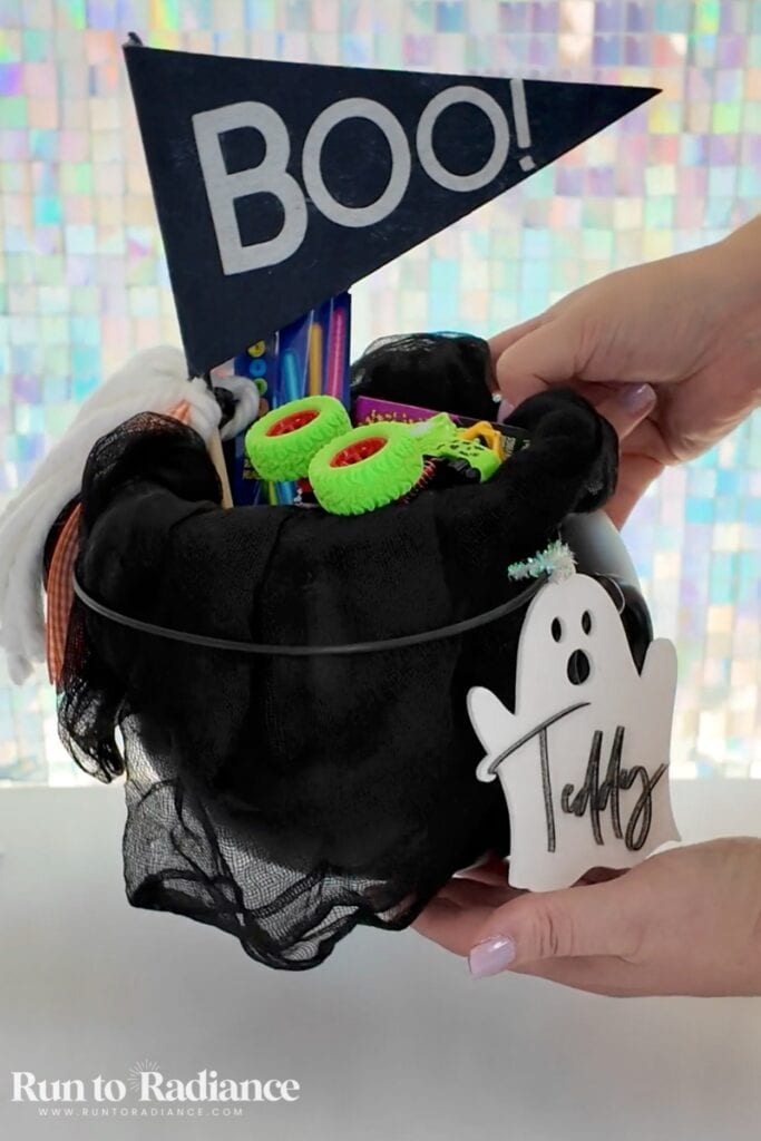 woman holding a black cauldron stuffed with toys as a boy's boo basket