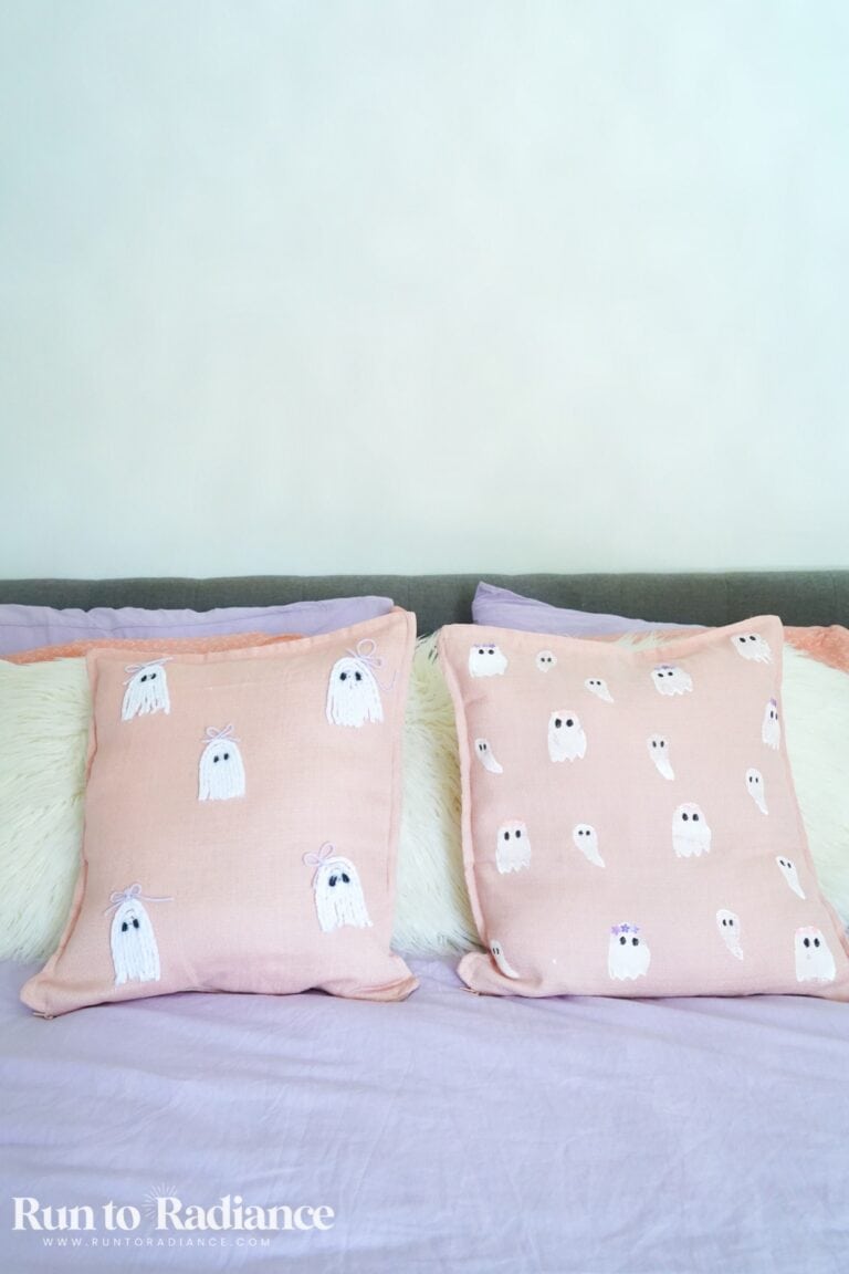Pink DIY ghost pillows on a bed with purple bedding