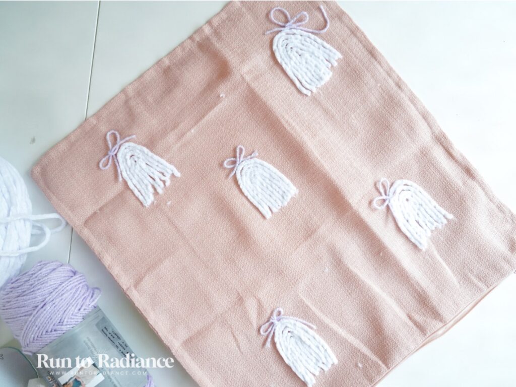 close up of a pillow with ghosts made from yarn