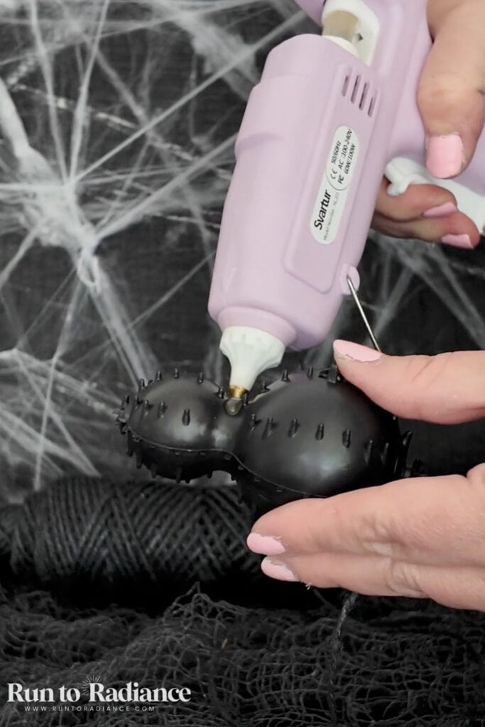 Hot gluing twine onto a spider for a dollar tree halloween craft