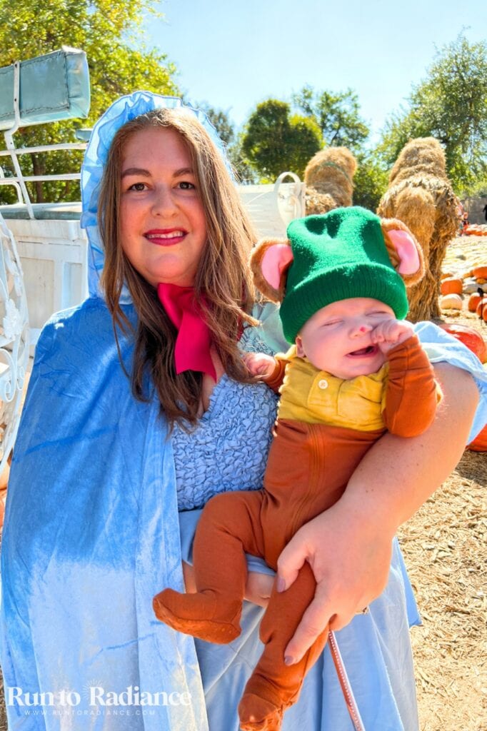 Mother and son halloween costume that's cinderella themed. Mom is dressed as a fairy godmother holding baby gus gus