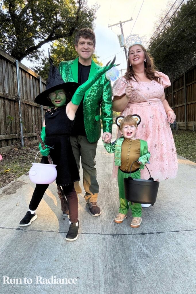 Family of four wearing Wicked and Oz inspired Halloween costumes with Glinda and Elphaba and a flying monkey