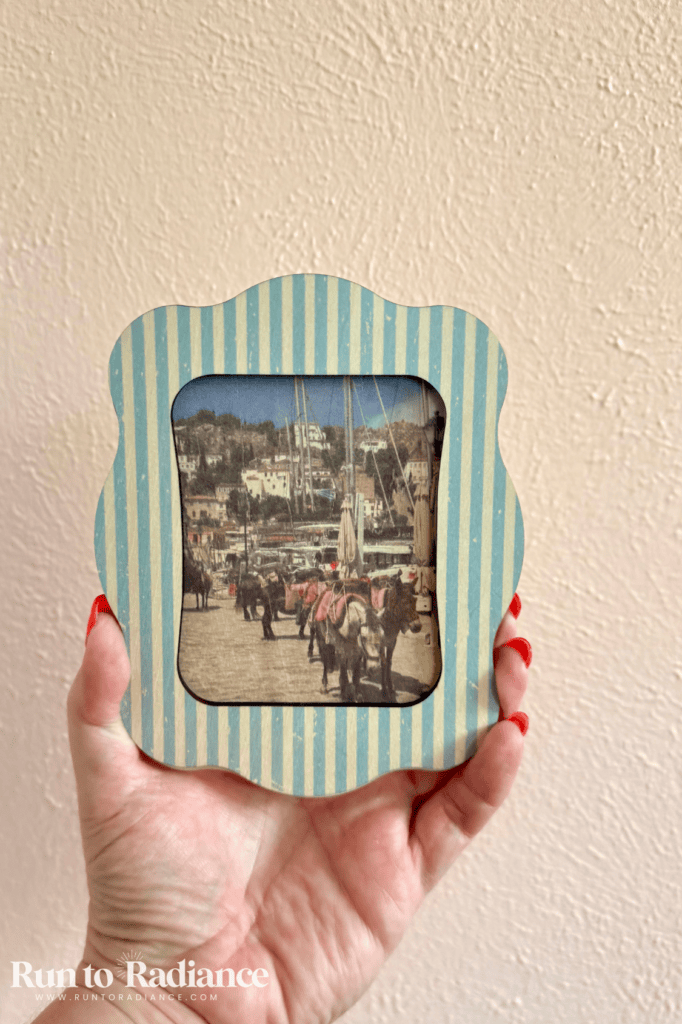 Hand holding a finished striped scalloped frame with a vintage-style photo insert